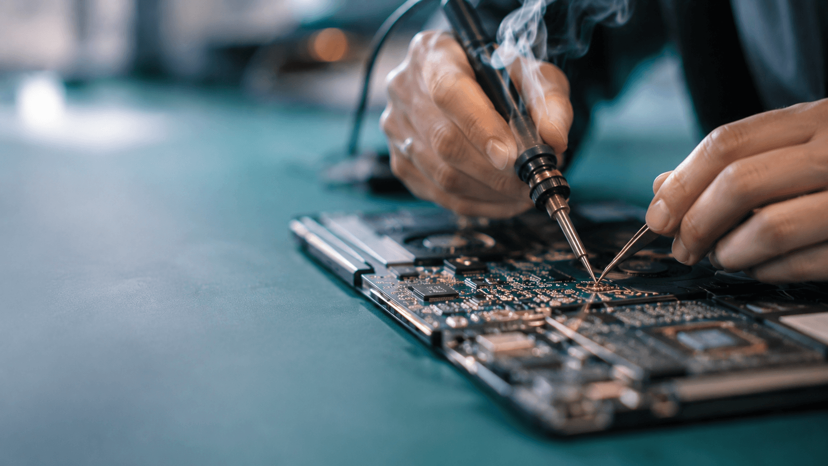 Close-up of a technician soldering a MacBook logic board at Motech Computers