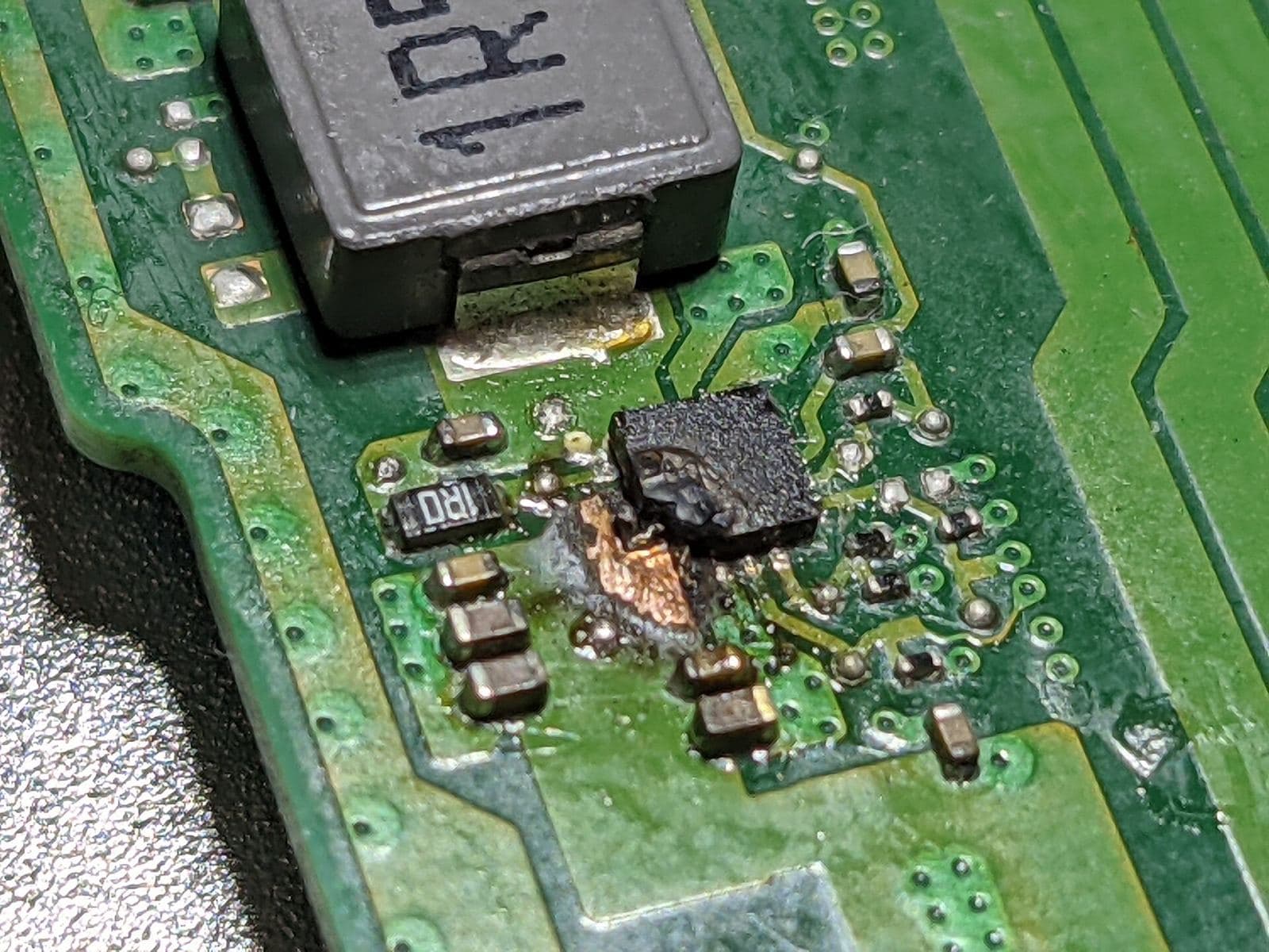 Microscope close-up of a laptop logic board during a component-level motherboard repair