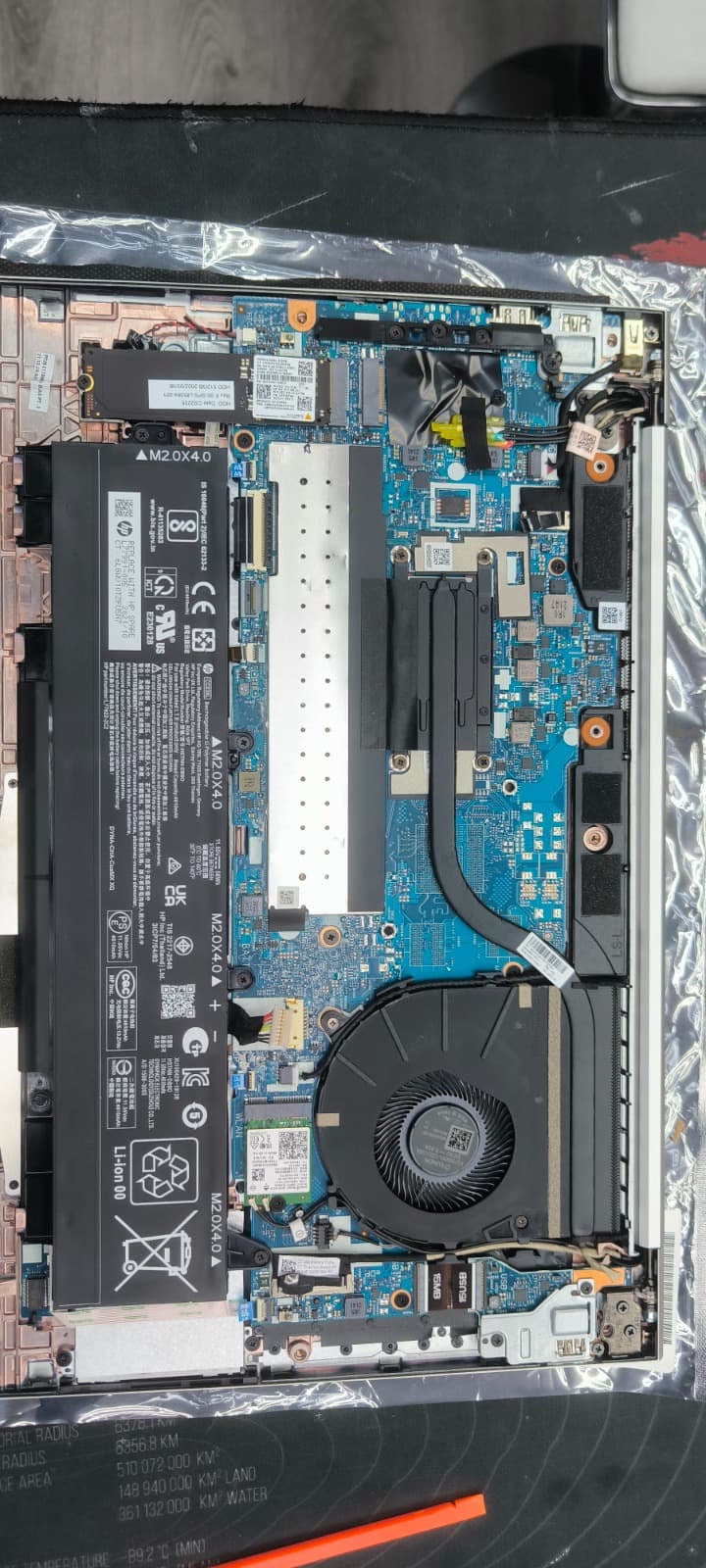 Open HP laptop showing motherboard, battery and cooling fan during a laptop repair