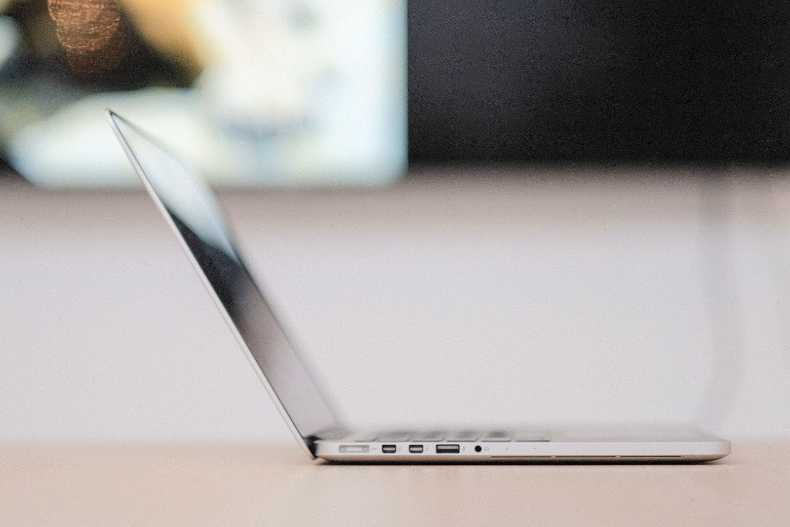 MacBook laptop viewed from the side, resting on a workbench ahead of an Apple Mac repair